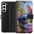 Pikkukuva 1 / 3: Yhteensopiva Lompakkokotelo Samsung Galaxy S23+ Sininen Stitchistä inspiroitunut piirroshahmo kukkien ympäröimässä luontomaisemassa ja suloisella ilm