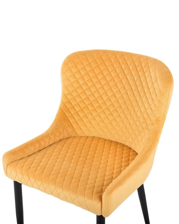 Et sæt med 2 polstrede stole i gul velour med sorte metalben til en spisestue i retro glamourstil