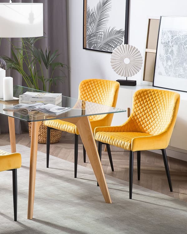 Et sæt med 2 polstrede stole i gul velour med sorte metalben til en spisestue i retro glamourstil