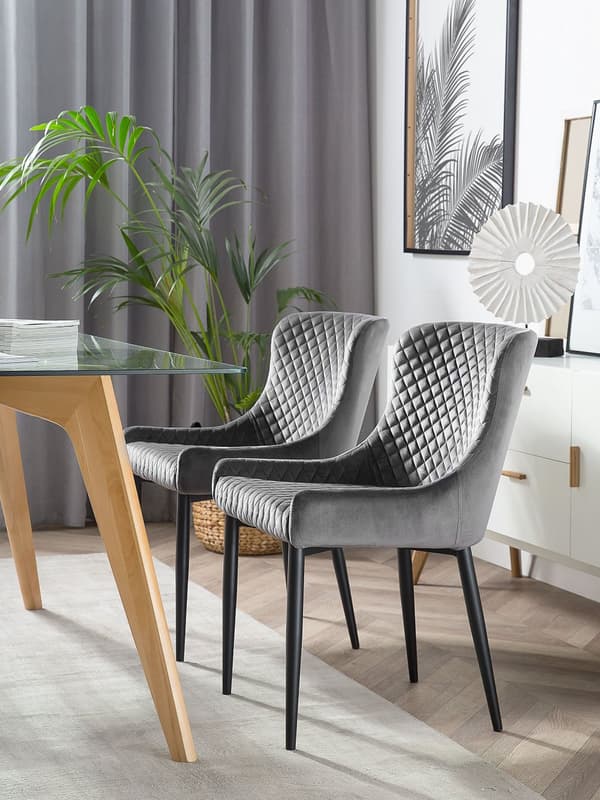 Et sæt med 2 grå velourpolstrede stole med sorte metalben til en spisestue i retro glamourstil