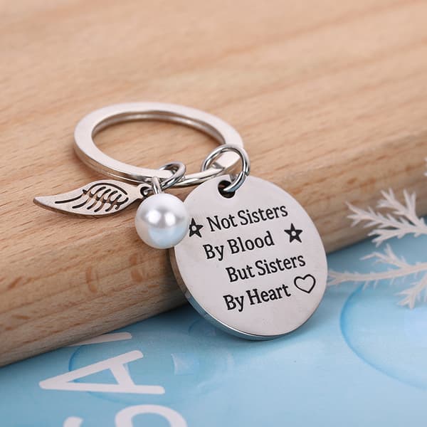 INF Nøkkelring med vinge og merke med teksten "Sisters by Heart"