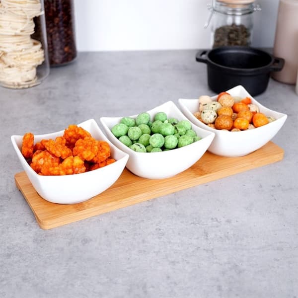 Tre elegante porcelænsskåle på bambusbakke til snacks og dips